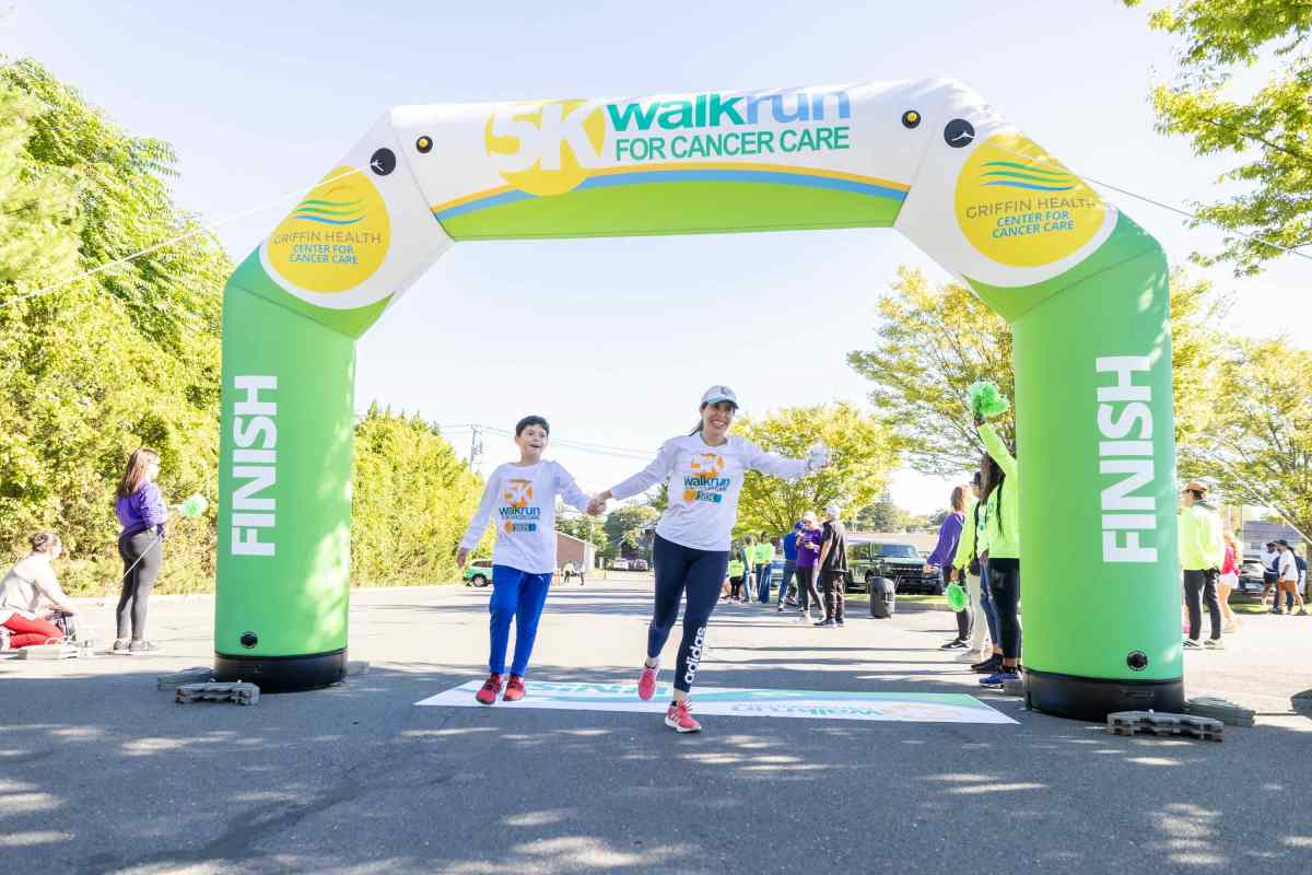 Runners or walkers cross the finish line at the 2025 cancer center fundraiser.